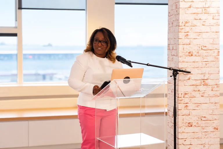 Nathalia speaking at a conference behind an acrylic lectern